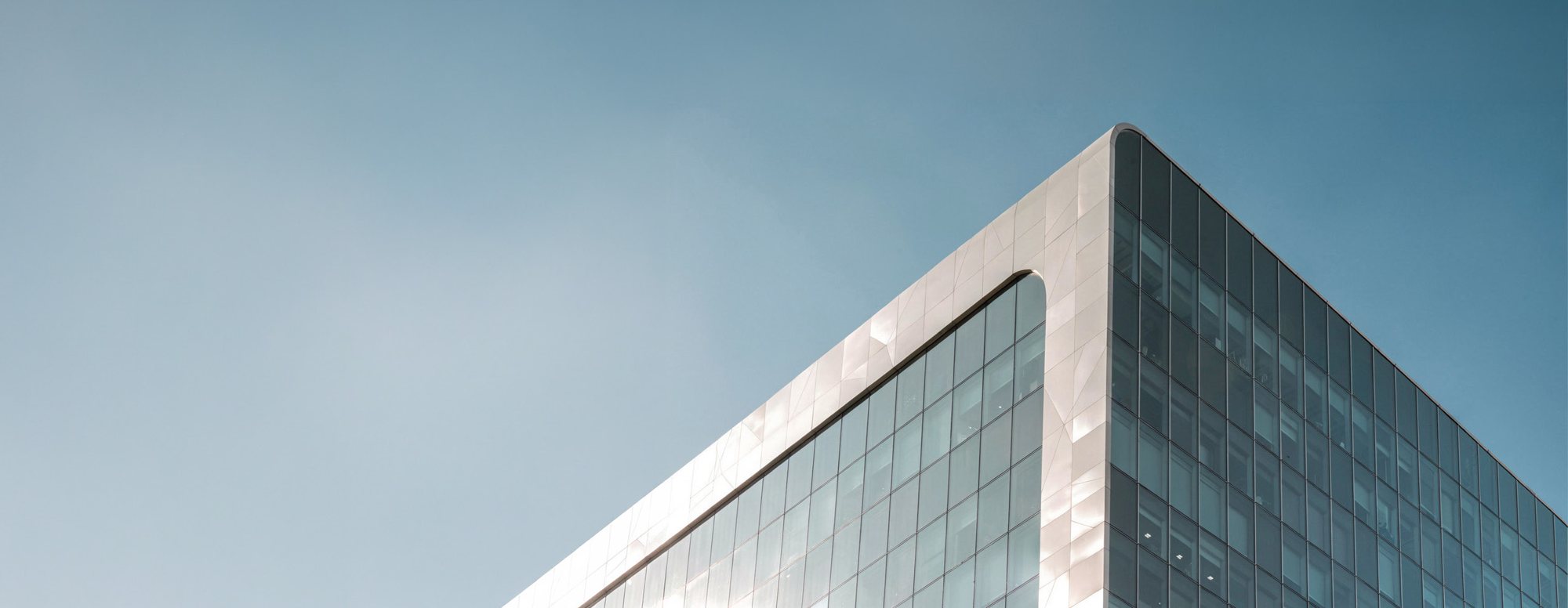 Glass tower corner against a pale blue sky